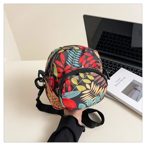 Detail of floral canvas crossbody bag featuring tropical leaf patterns and zipper pockets