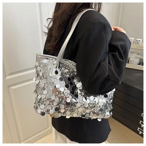 Detail of silver sequin bucket bag featuring high-shine metallic finish on a black blazer