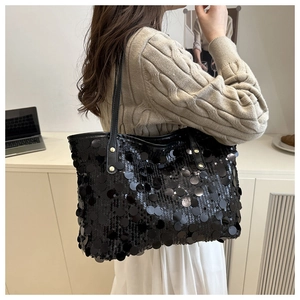 Detail of black sequined tote bag featuring reflective surface and gold rivets