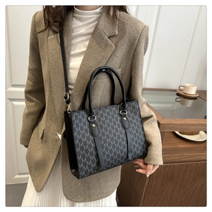 Classic M-pattern letter print handbag worn by a model in a brown suit for office style