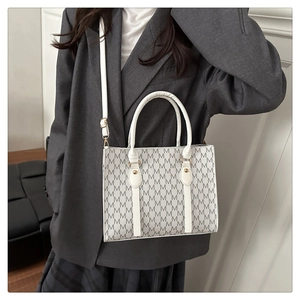White tote bag with M-letter print shown on model with shoulder strap and gold hardware