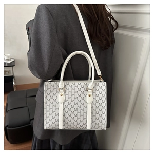 Model wearing a white monogram tote bag with top handles and adjustable shoulder strap
