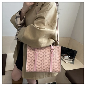 Side view of pink tote bag with brown M patterns and metal accents on a trench coat