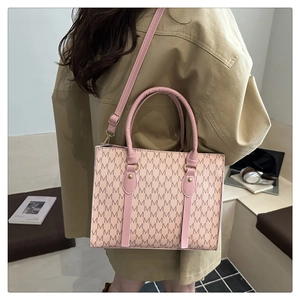 Detail of a pink and beige crossbody bag with M-pattern print and adjustable shoulder strap