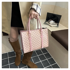 Detailed macro view of a pink monogram tote bag with gold metal hardware and slim handles