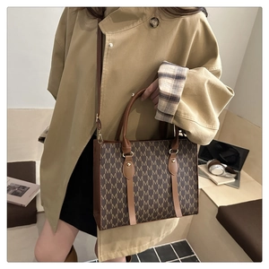 Detail of vintage brown tote bag with M-pattern print and adjustable leather strap