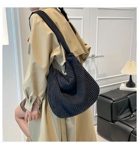 Detail of black corduroy hobo bag showing thick ribbed texture on a khaki coat