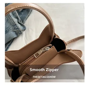 Detail of the smooth metal zipper closure on the light brown kitten tote bag