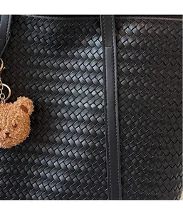 Gros plan sur la texture du sac cabas tressé noir avec un petit ours en peluche marron