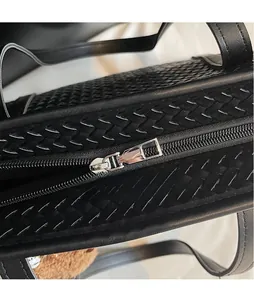 Détail de la fermeture éclair argentée et du cuir tressé noir du sac fourre-tout
