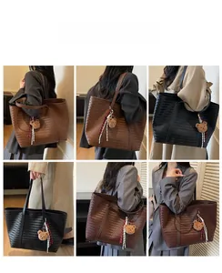 Vues détaillées de grands sacs cabas en cuir tressé noir et marron avec breloque ours
