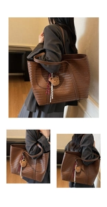 Détail d'un grand sac cabas tressé marron avec breloque ours et cordon rayé décoratif