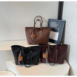 Détail de sacs cabas tissés en noir et marron avec des breloques ours mignon