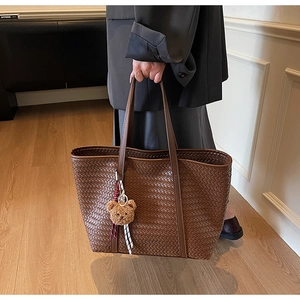 Dettaglio della borsa tote intrecciata marrone scuro con ciondolo a forma di orsetto