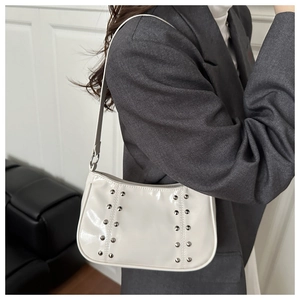 Détail du sac sous le bras en cuir verni blanc avec rivets argentés et fini brillant