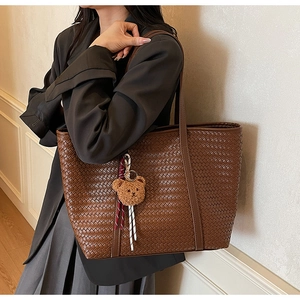 Vista dettagliata della borsa tote intrecciata marrone con ciondolo a forma di orso