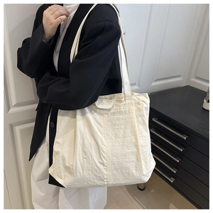Détail d'un grand sac cabas en nylon blanc cassé avec une étiquette de mode épurée