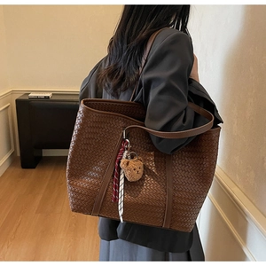 Dettaglio borsa shopper grande in pelle intrecciata marrone con ciondolo a orsetto