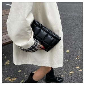 Détail de la pochette matelassée noire tenue par un mannequin dans une scène de rue