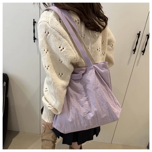 Close-up of pleated light purple tote bag with fashion tag and single shoulder strap