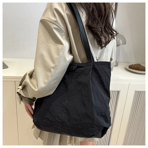 Detail of the black tote bag showing wrinkled nylon texture and FASHION label