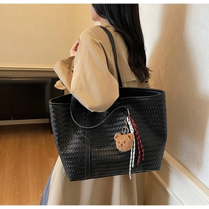 Dettaglio borsa shopper nera intrecciata con ciondolo a orsetto e tracolla in pelle