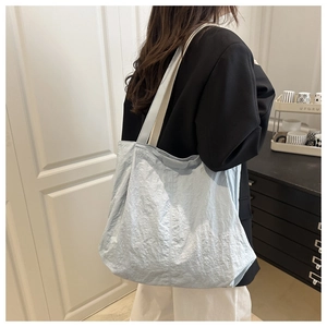 Détail du sac cabas en nylon bleu clair à texture froissée porté par un mannequin chez soi