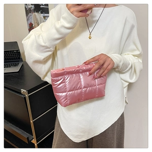 Détail d'une pochette en satin matelassé rose avec une texture douce rembourrée
