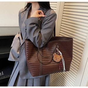 Dettaglio della borsa tote intrecciata marrone scuro con ciondolo a orso e corda decorativa