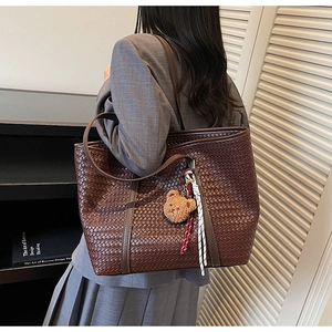 Dettaglio della borsa tote in pelle intrecciata marrone scuro con ciondolo a forma di orso