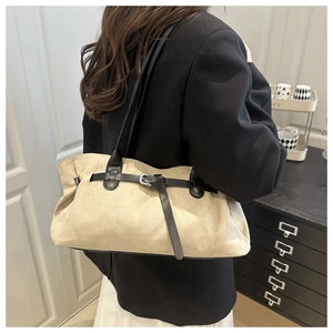 Beige suede shoulder bag with thin black straps and metal buckle detail worn by a model