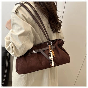 Close-up of brown suede hobo bag with wooden bead charm and side buckle detail