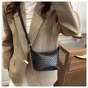 Detailed view of the black woven leather hobo bag with adjustable strap worn by a model