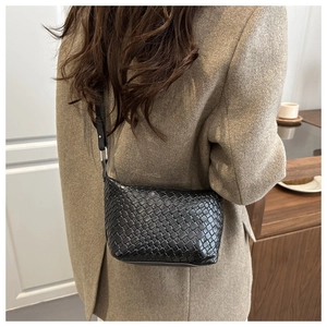 Detailed view of black woven leather texture on a minimalist dumpling shaped crossbody bag