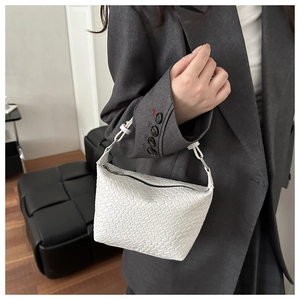 Detailed view of a white woven leather handbag featuring silver hardware and black zipper