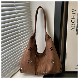 Detaillierte lasergeschnittene Blumenmuster auf brauner Wildledertasche im Studio