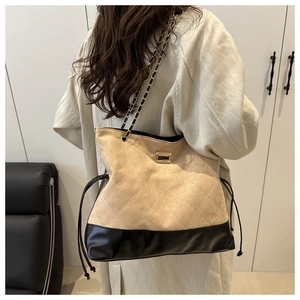Detail of stitched quilted suede tote with gold hardware and chain strap on shoulder