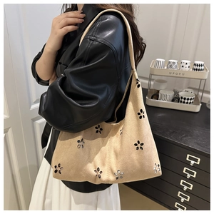 Détail du motif floral découpé au laser sur le sac cabas en daim beige porté par le modèle
