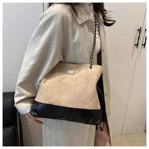 Detail of quilted beige and black crossbody bag with metal chain strap and luxury texture
