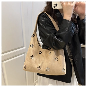 Détail de motifs floraux découpés au laser sur un sac à bandoulière en daim beige