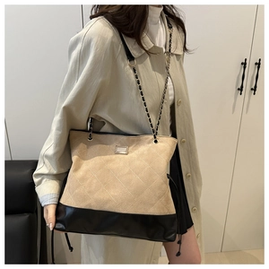 Close-up of quilted beige suede tote with gold chain strap and metal hardware detail