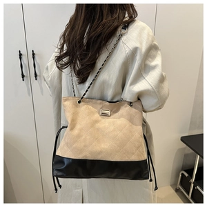 Detail of quilted suede shoulder bag with chain strap and elegant patchwork design
