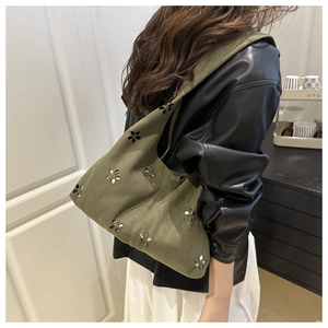 Dettaglio della borsa a spalla in maglia verde scuro con motivi floreali traforati