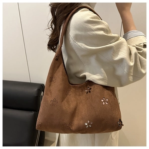 Vue détaillée d'un sac cabas en daim marron avec des motifs floraux découpés au laser