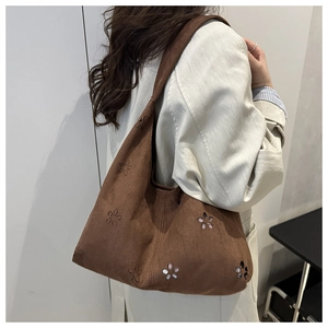 Détail de motifs floraux découpés au laser et perles sur sac hobo en daim marron