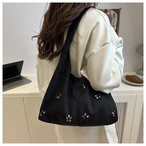 Detail view of the black tote bag with laser-cut floral patterns on a wide strap