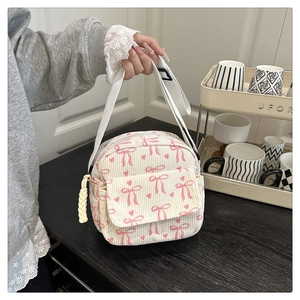 Détail du sac bandoulière en velours côtelé crème avec motifs de nœuds roses et zip