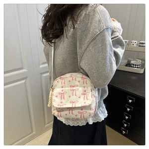 Modèle portant un sac bandoulière en velours côtelé blanc avec motifs de nœuds roses