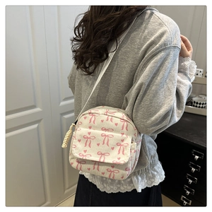 Détail du velours côtelé blanc cassé avec nœuds roses et cœurs rouges sur le sac à main