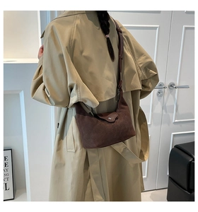 Detail view of dark brown suede hobo bag with adjustable strap on a female model